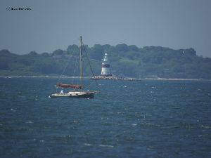 A sailboat passes by the Latimer Reef Lighthouse.