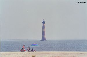 People play on the beach near the lighthouse.