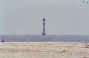 People fish near the lighthouse.