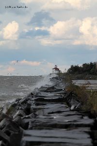 Waves smash against the breakwall.