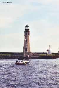 A sailboat passes by the Main Lighthouse.