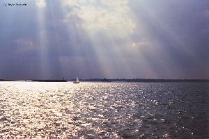 A sailboat passes the intake light at dusk.