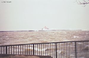Waves crash over the breakwall.