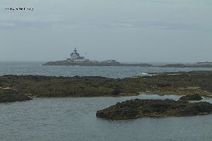 The Cuckolds Lighthouse with rocks in the foreground.