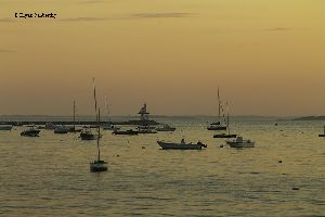 Ships anchored by the Dog Bar Breakwater Light, at sunset.