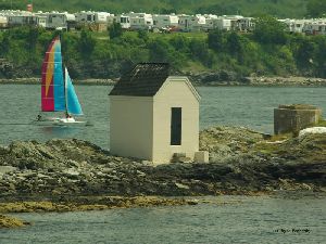 A sailboat by the lighthouse.