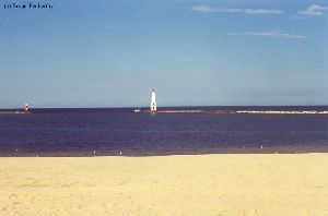 A distance shot of the lighthouse and a boat.