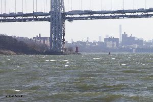 Traffic moving over the George Washington Bridge, the lighthouse is underneath.
