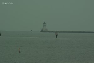 The lighthouse stands at the end of a pier.