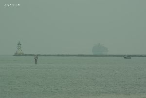 A container ship passes the lighthouse.