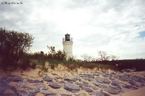 The top of the lighthouse, sand dunes, and rocks.