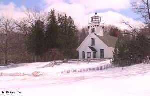 A recent snowfall surrounds the lighthouse.