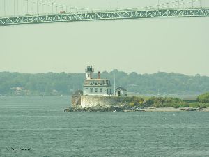 The lighthouse sits on an island near the bridge.