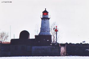 Lighthouse with ice in harbor.
