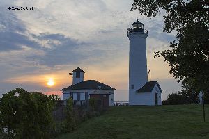 Tibetts Point Lighthouse and fog horn building at sunset.